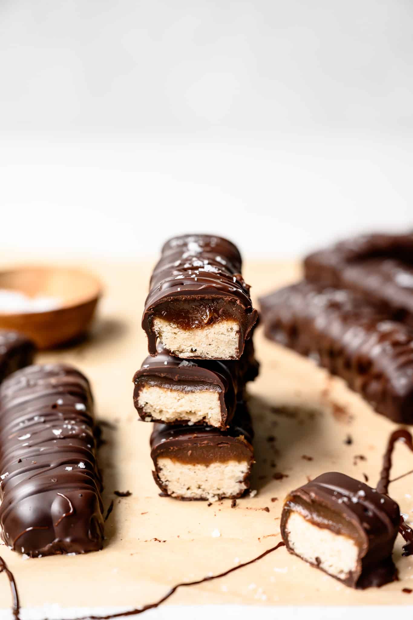 side view of 3 vegan twix bars stacked on parchment paper and cut in half to show filling