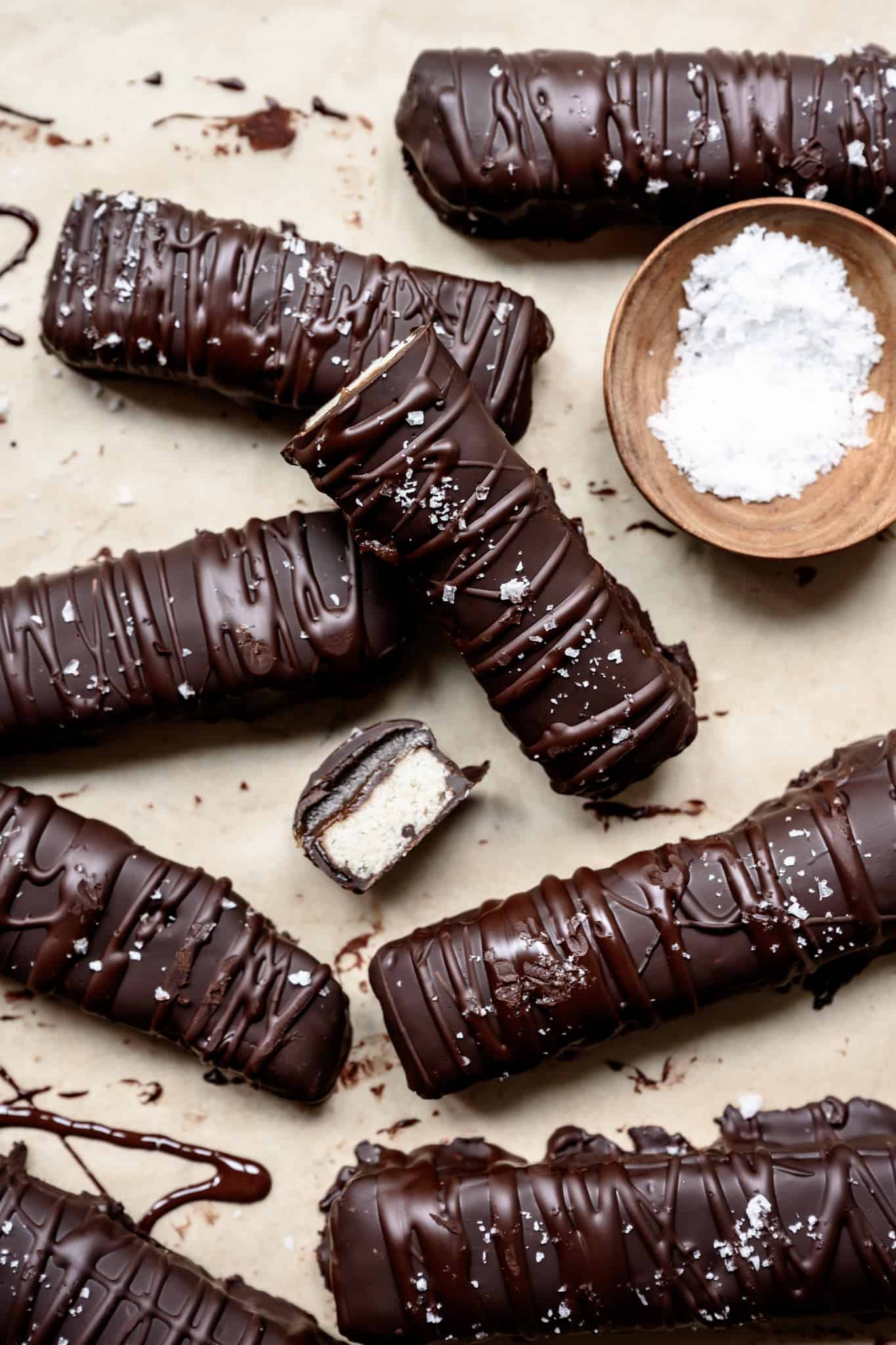 overhead view of homemade vegan and gluten free twix bars with flaky sea salt on parchment paper