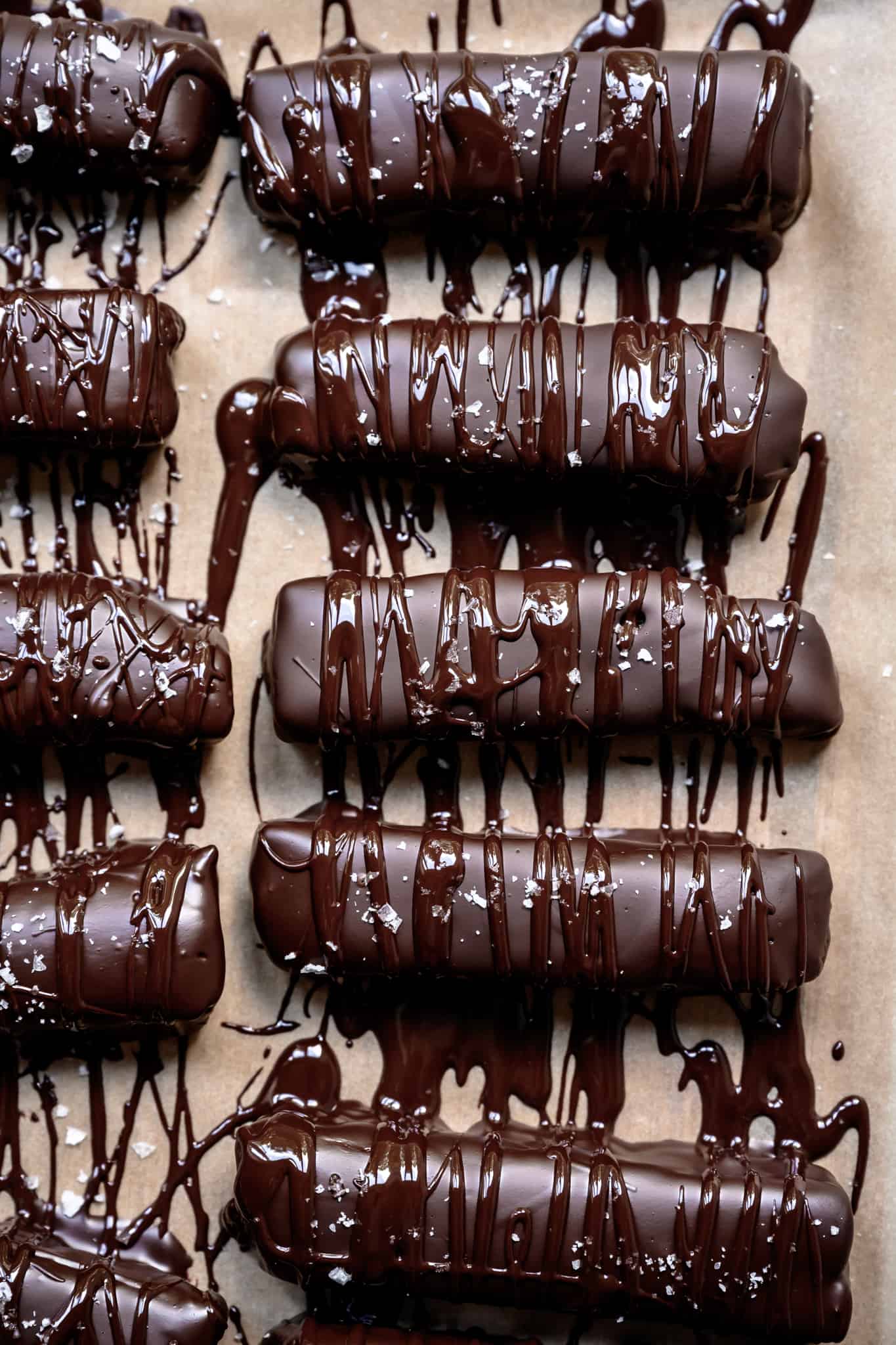 overhead view of homemade twix bars with chocolate drizzle and salt on parchment paper