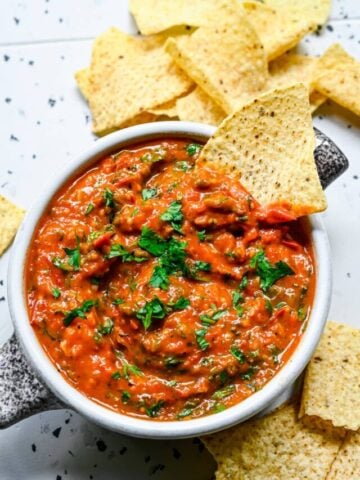 Close up view of cherry tomato salsa in a bowl with tortilla chips.