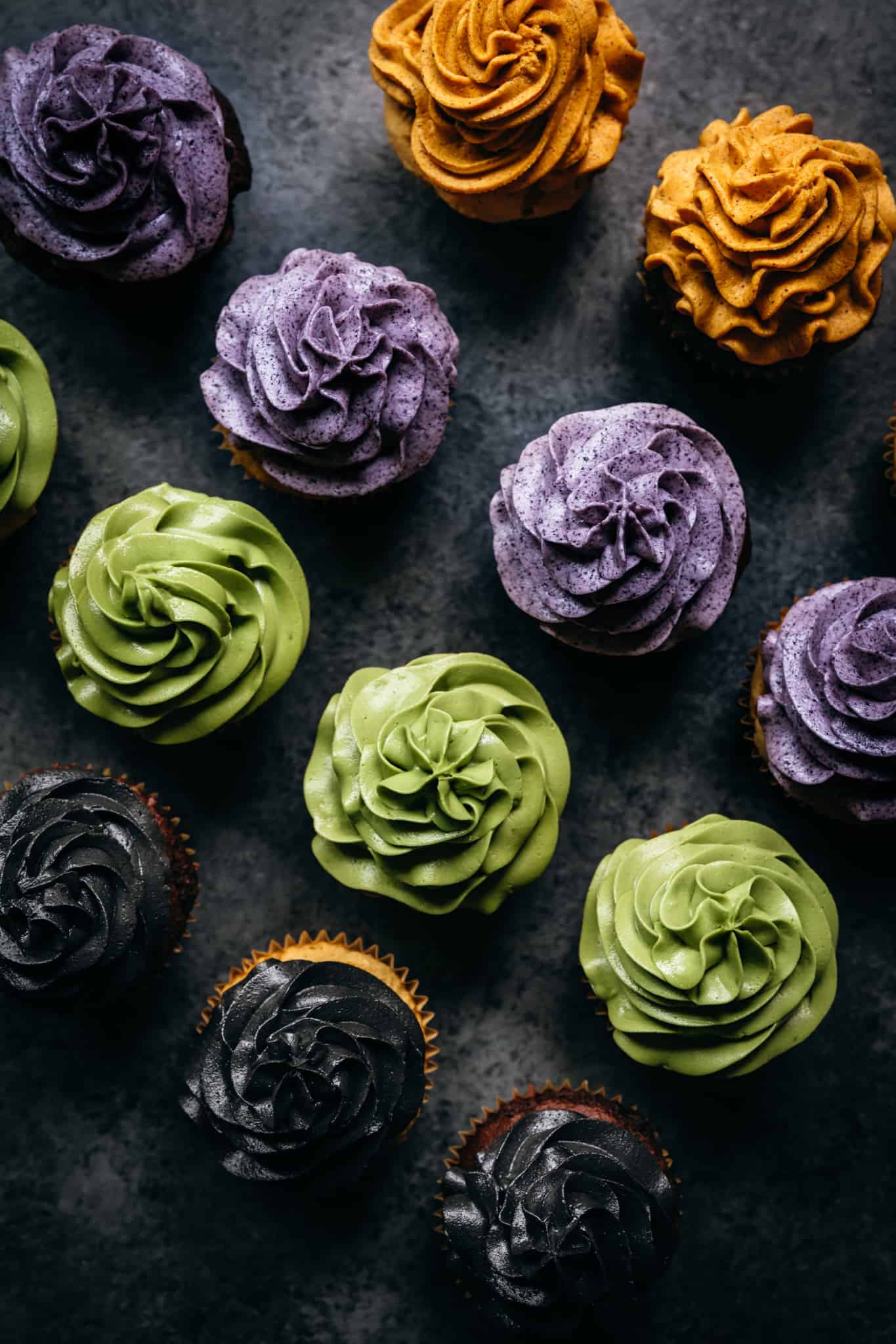 overhead of vegan gluten free cupcakes with frosting colored with natural food coloring