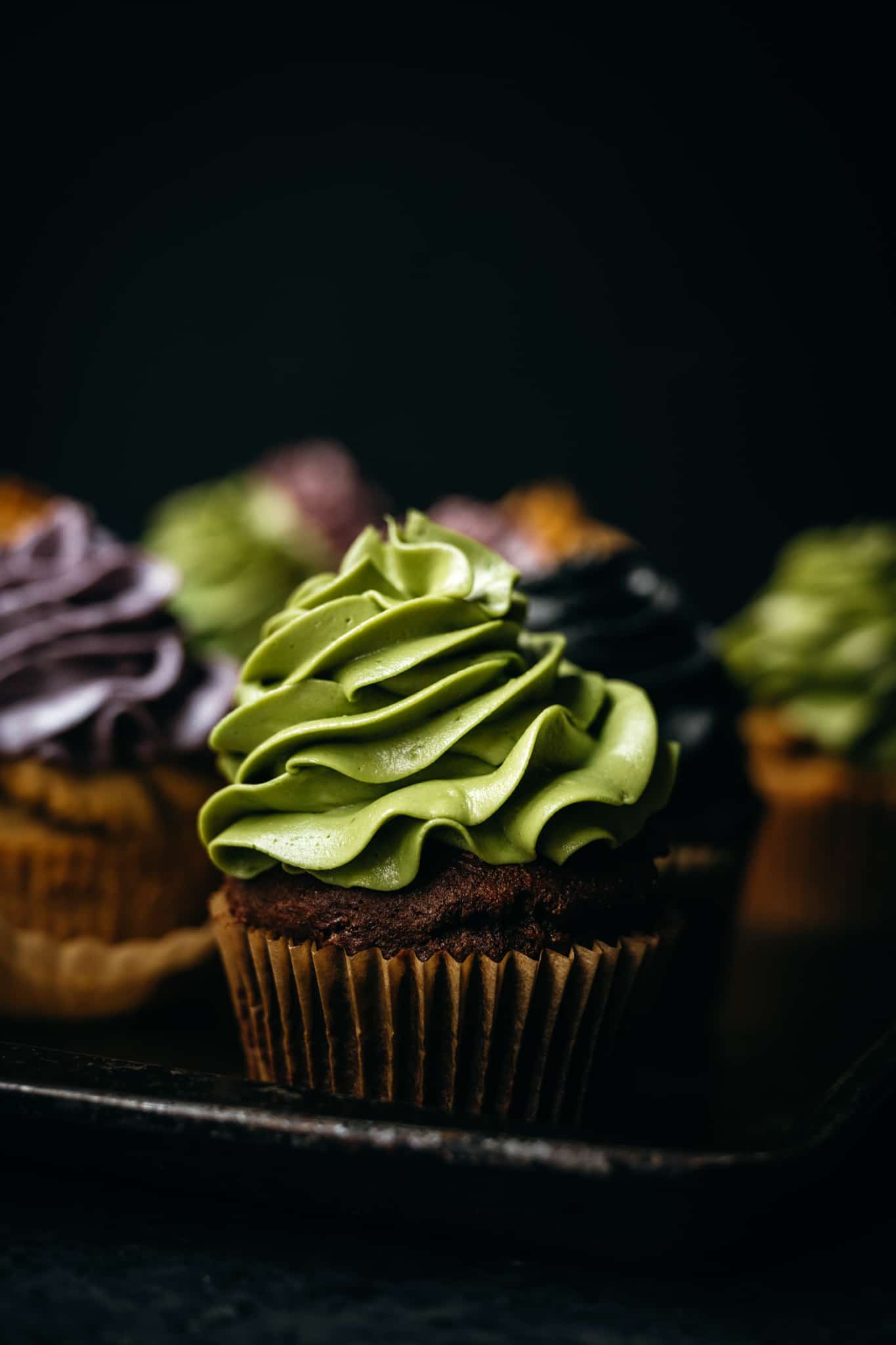 closeup side view of vegan chocolate cupcake with green frosting colored with matcha