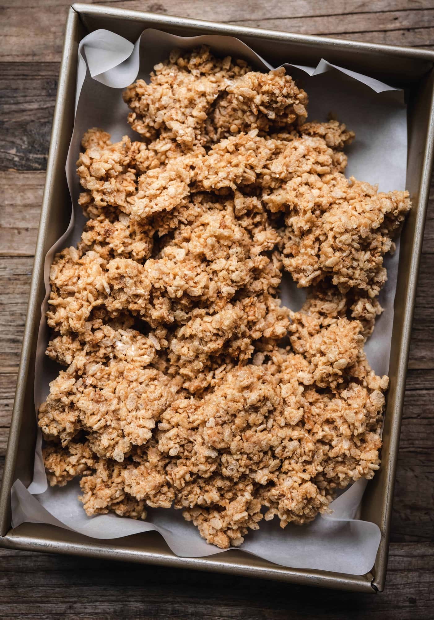 overhead of vegan peanut butter rice krispy dough in a prepared baking sheet before cooling