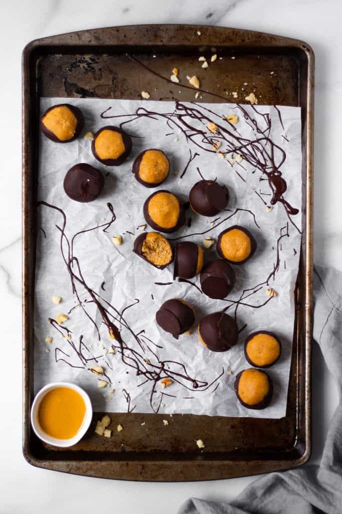 overhead of healthy peanut butter buckeyes on a baking dish with chocolate splatters
