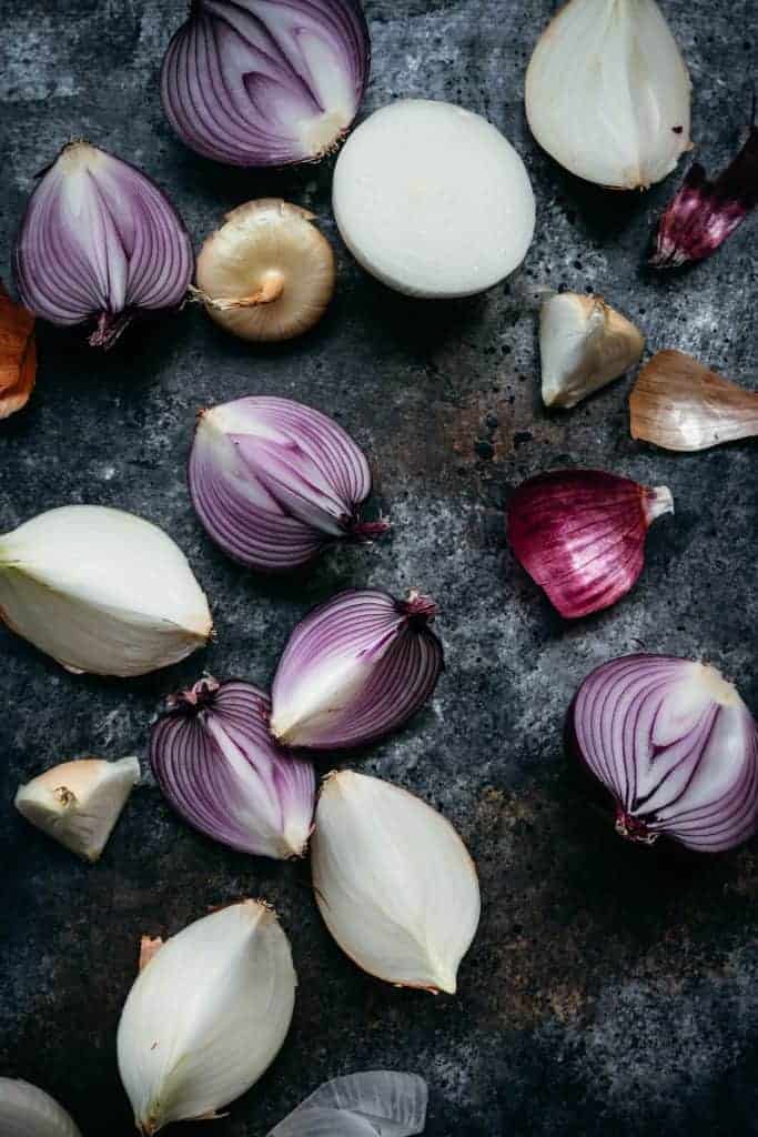 overhead of fresh purple onions chopped on a black background