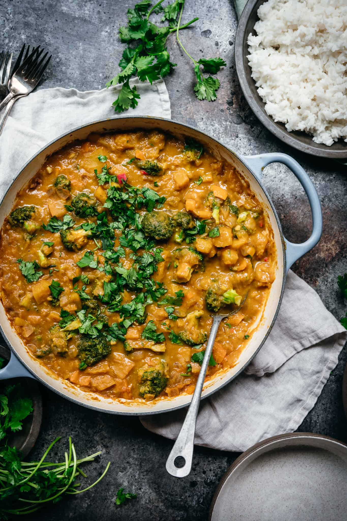overhead view of vegan pumpkin curry in a large pan on wood table