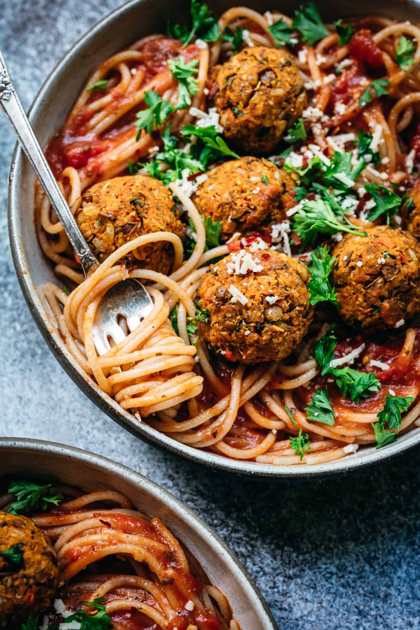 close up overhead of two bowls of spaghetti with vegan lentil meatballs and marinara sauce