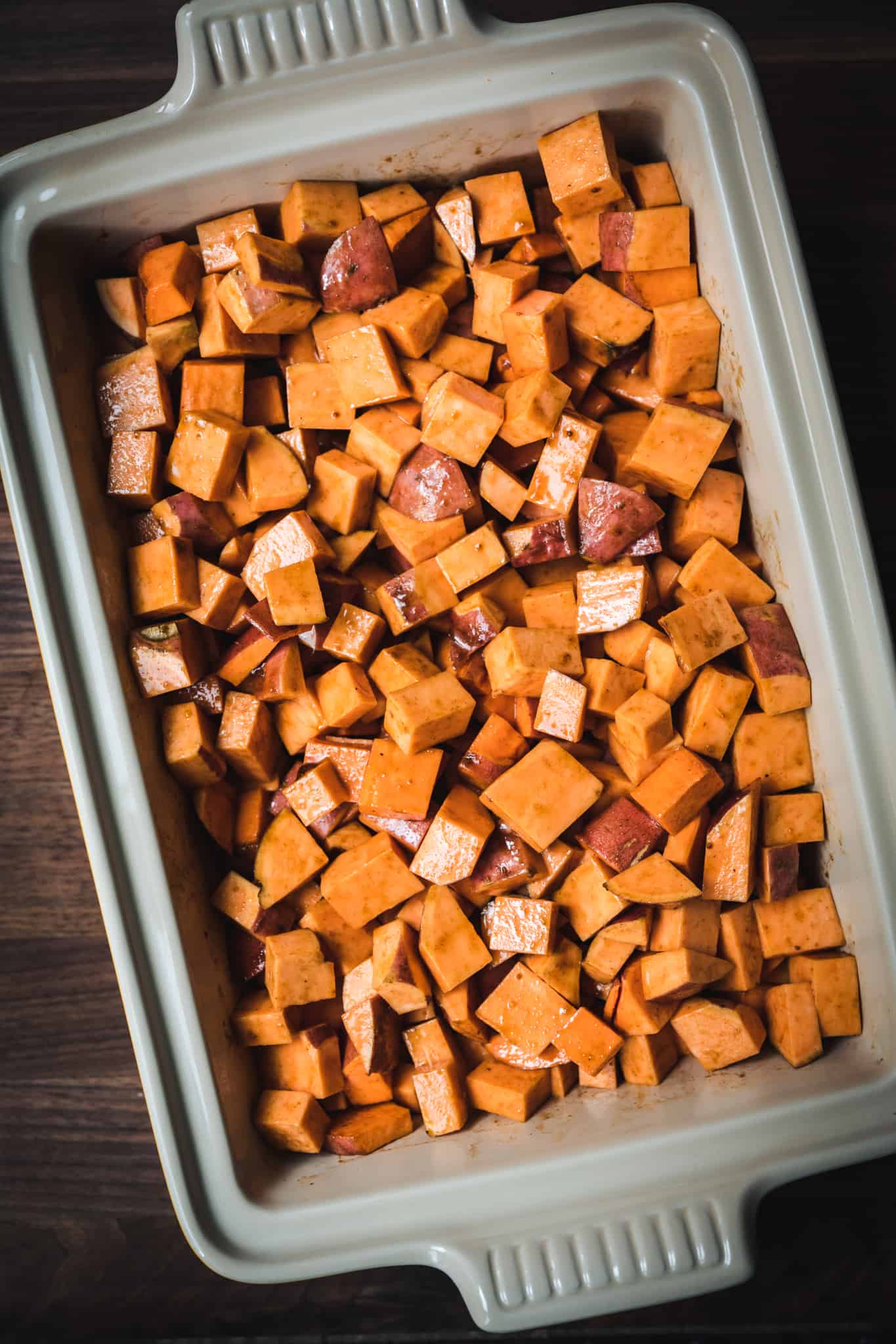 overhead view of diced sweet potatoes in casserole dish before baking