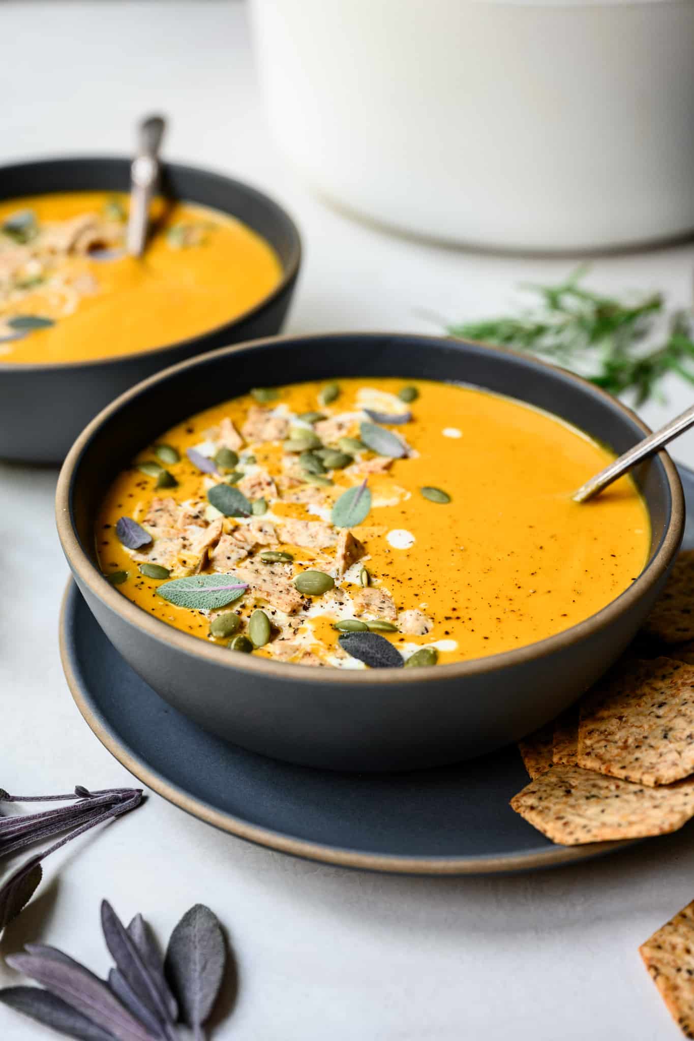 side view of vegan carrot apple soup in a grey bowl with spoon