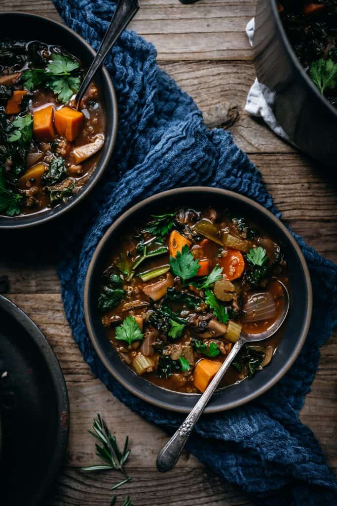 overhead view of 2 bowls of quinoa vegetable stew on wood table
