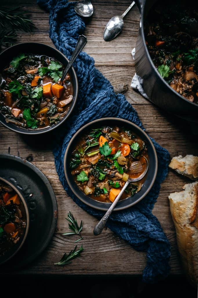 overhead view of 2 bowls of quinoa vegetable stew on wood table