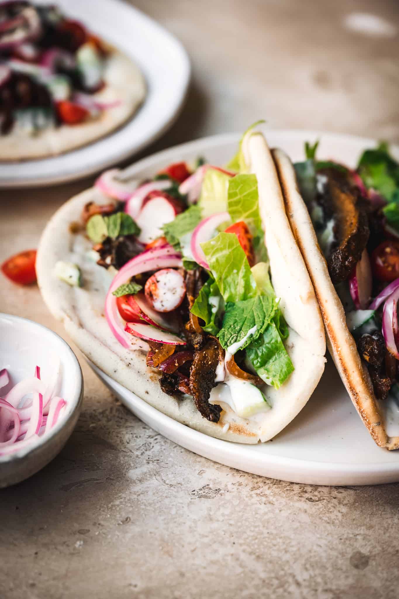 Close up side view of two mushroom shawarma in a pita bread on a white plate