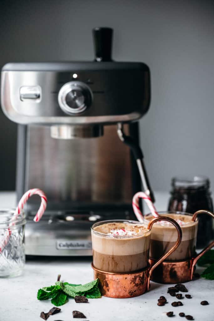 Two mugs of vegan peppermint mocha in front of espresso machine