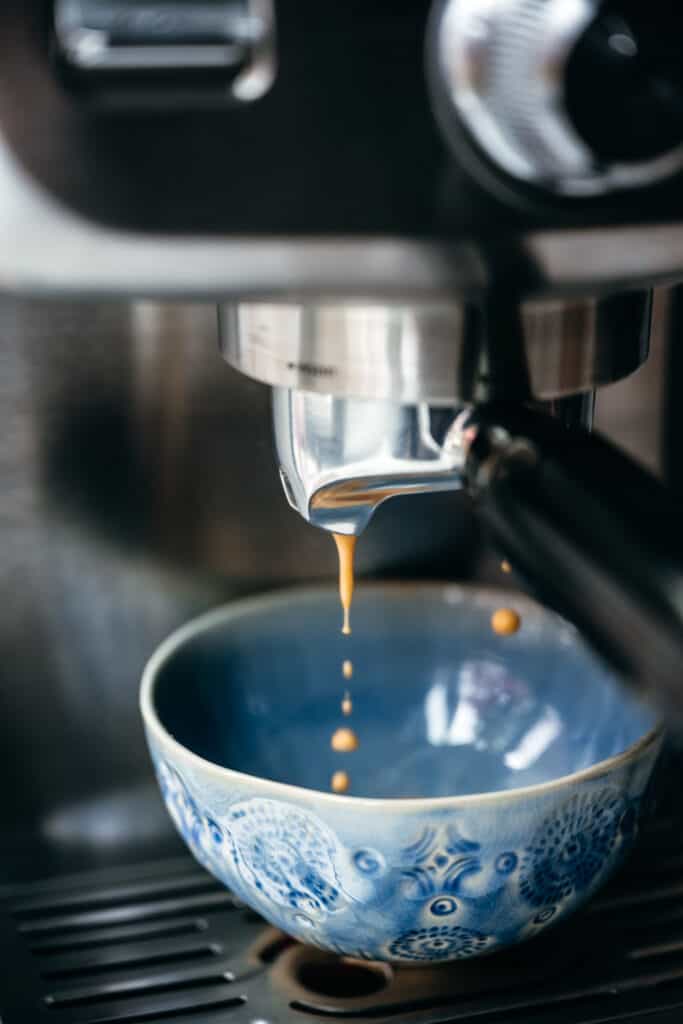Espresso falling into blue coffee cup from machine