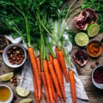 overhead of the raw ingredients for harissa roasted carrots on a wooden background