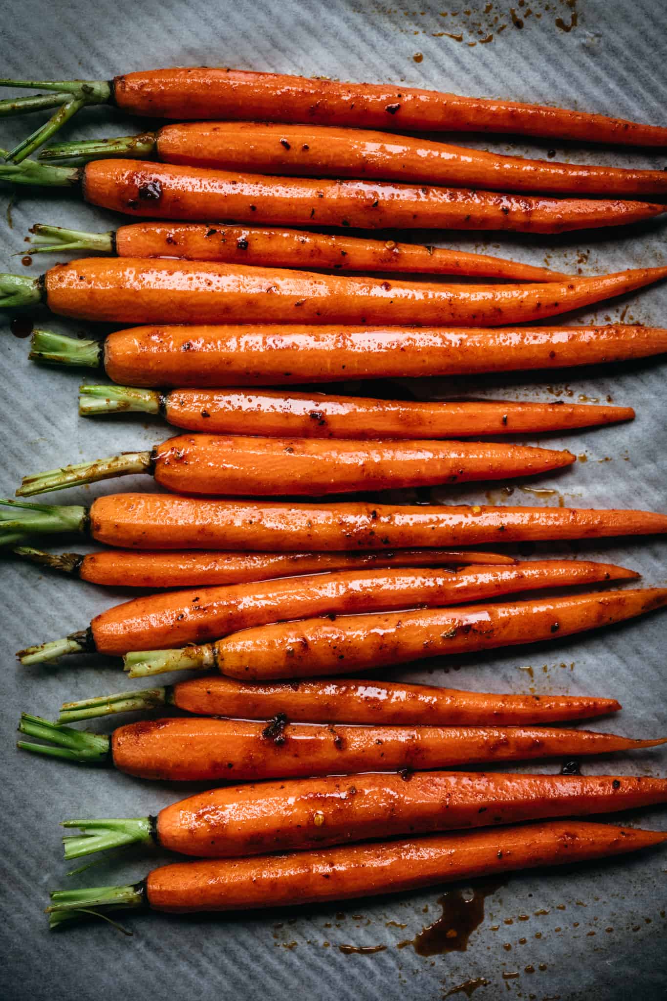 overhead of roasted carrots lined up on a metal baking sheet