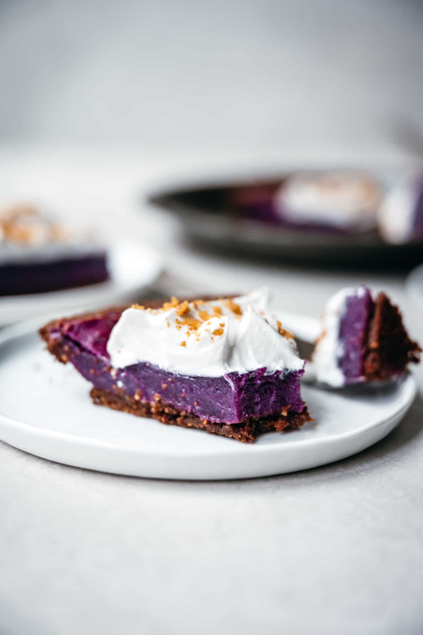 Side view of slice of vegan purple sweet potato pie on a white plate