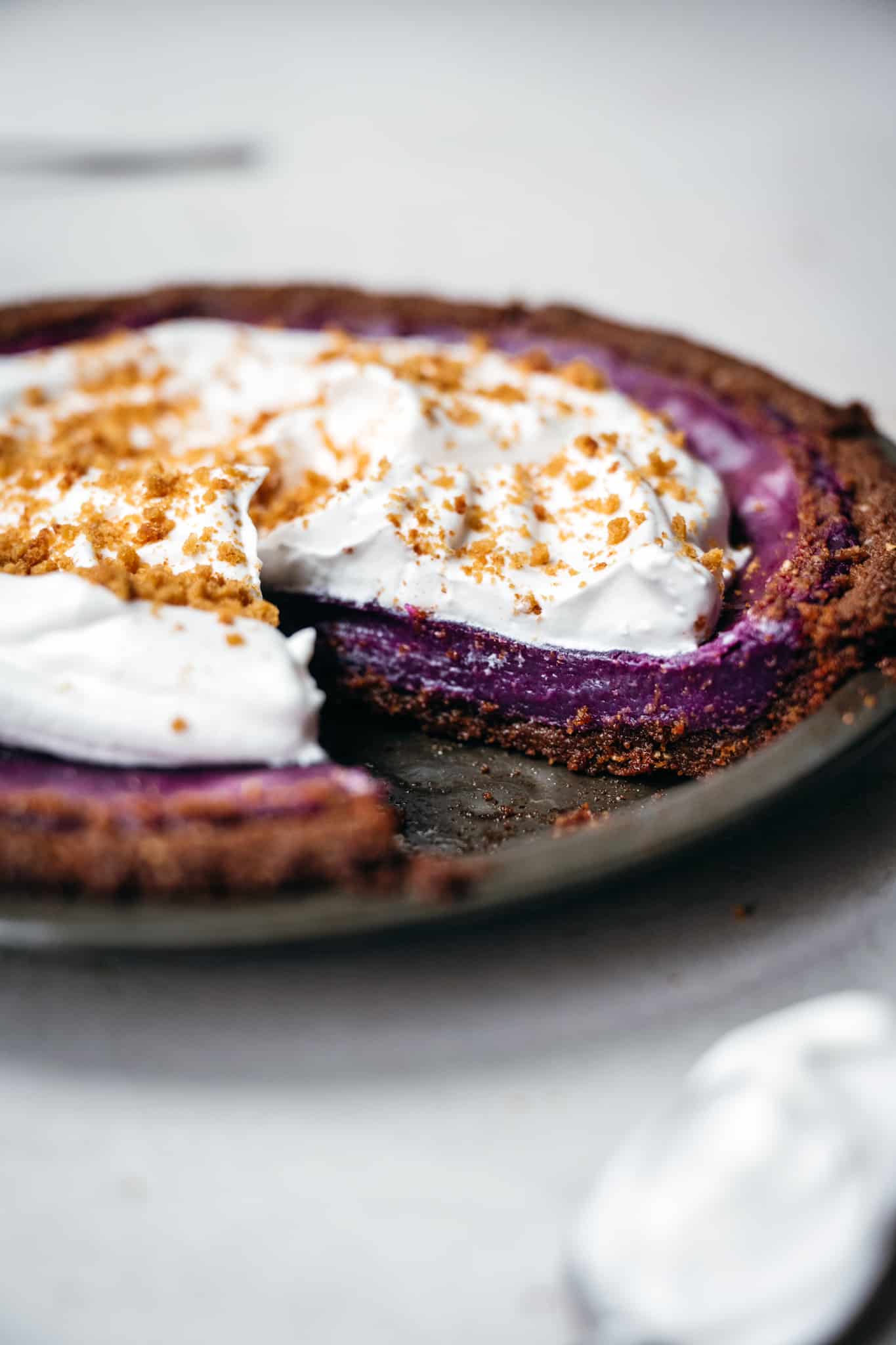 close up side view of purple sweet potato pie with whipped cream topping
