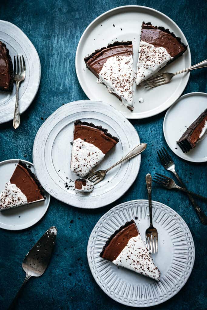overhead view of multiple white plates with slices of chocolate cream pie