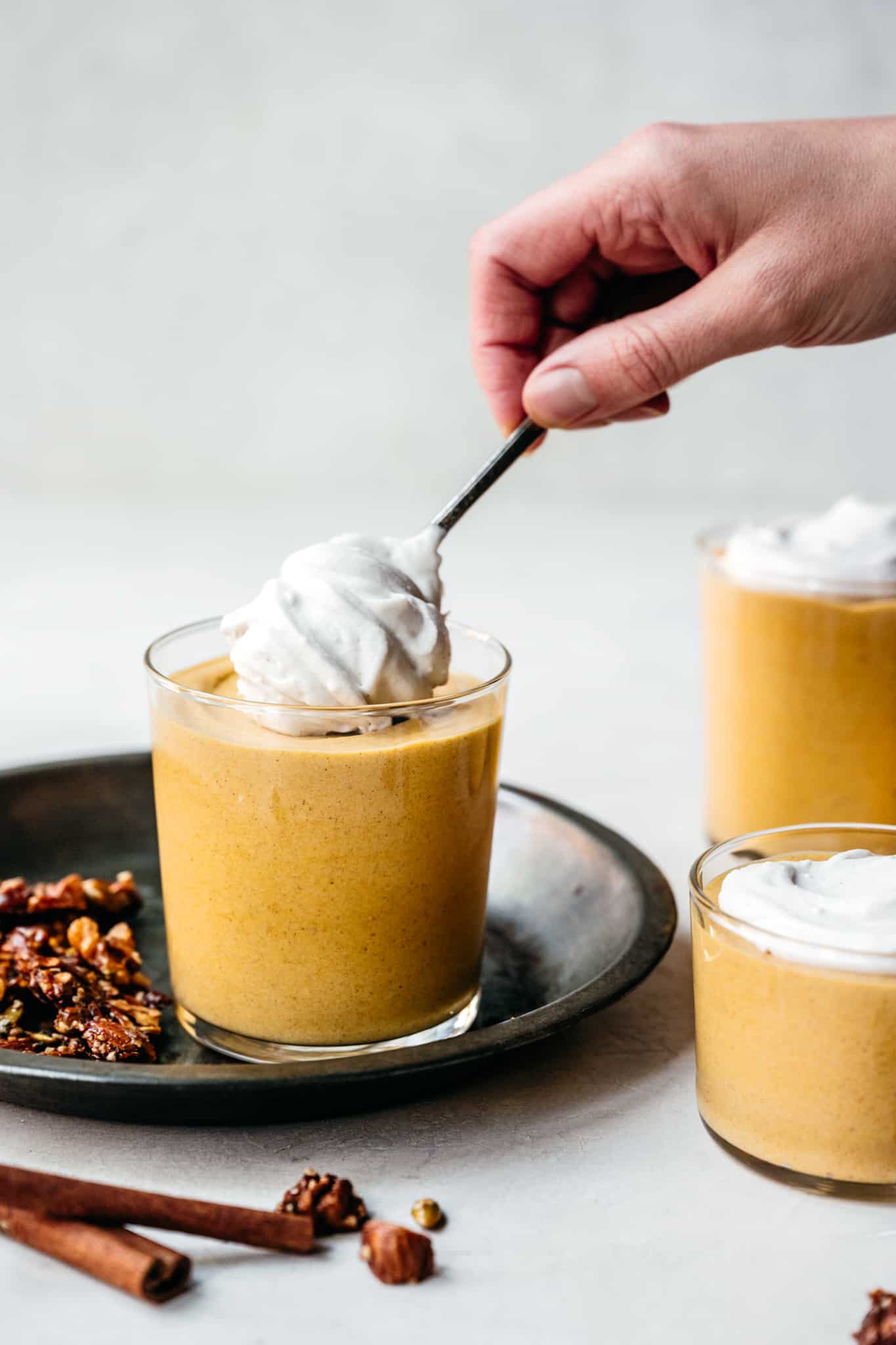 Side view of person spooning coconut whipped cream on top of mousse