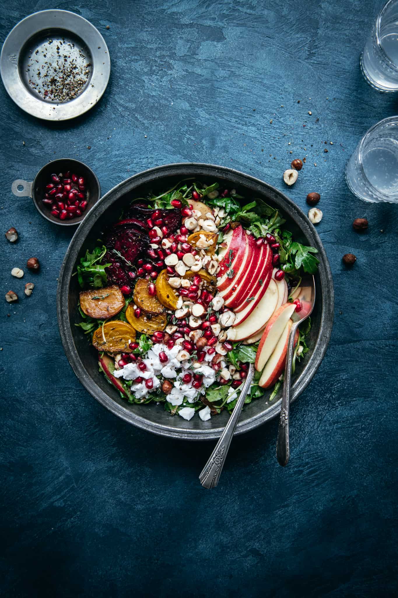 overhead view of beautiful roasted beet kale salad in a bowl on a blue background