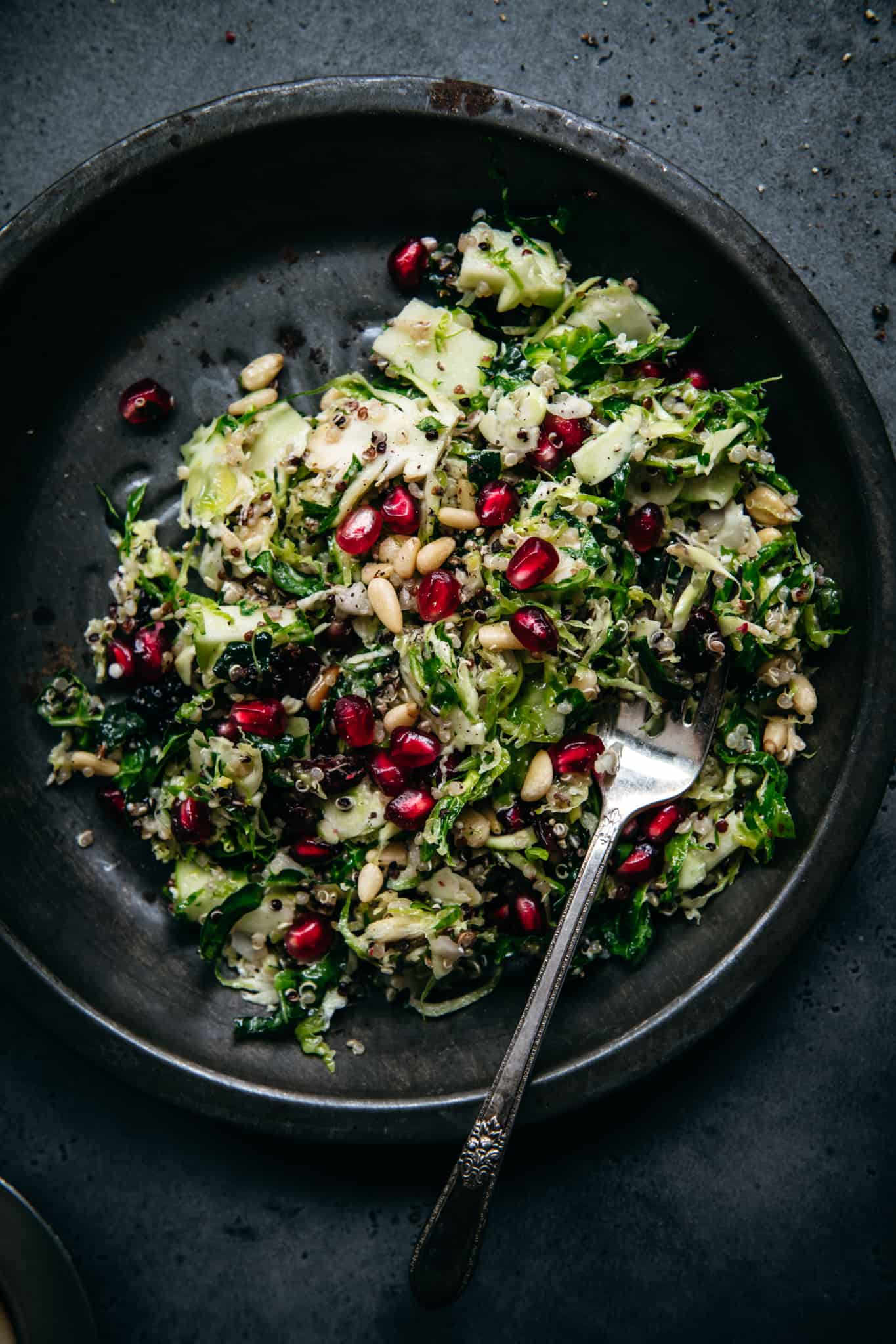 overhead of shaved brussels sprout salad with cranberry vinaigrette in a black bowl with a silver fork