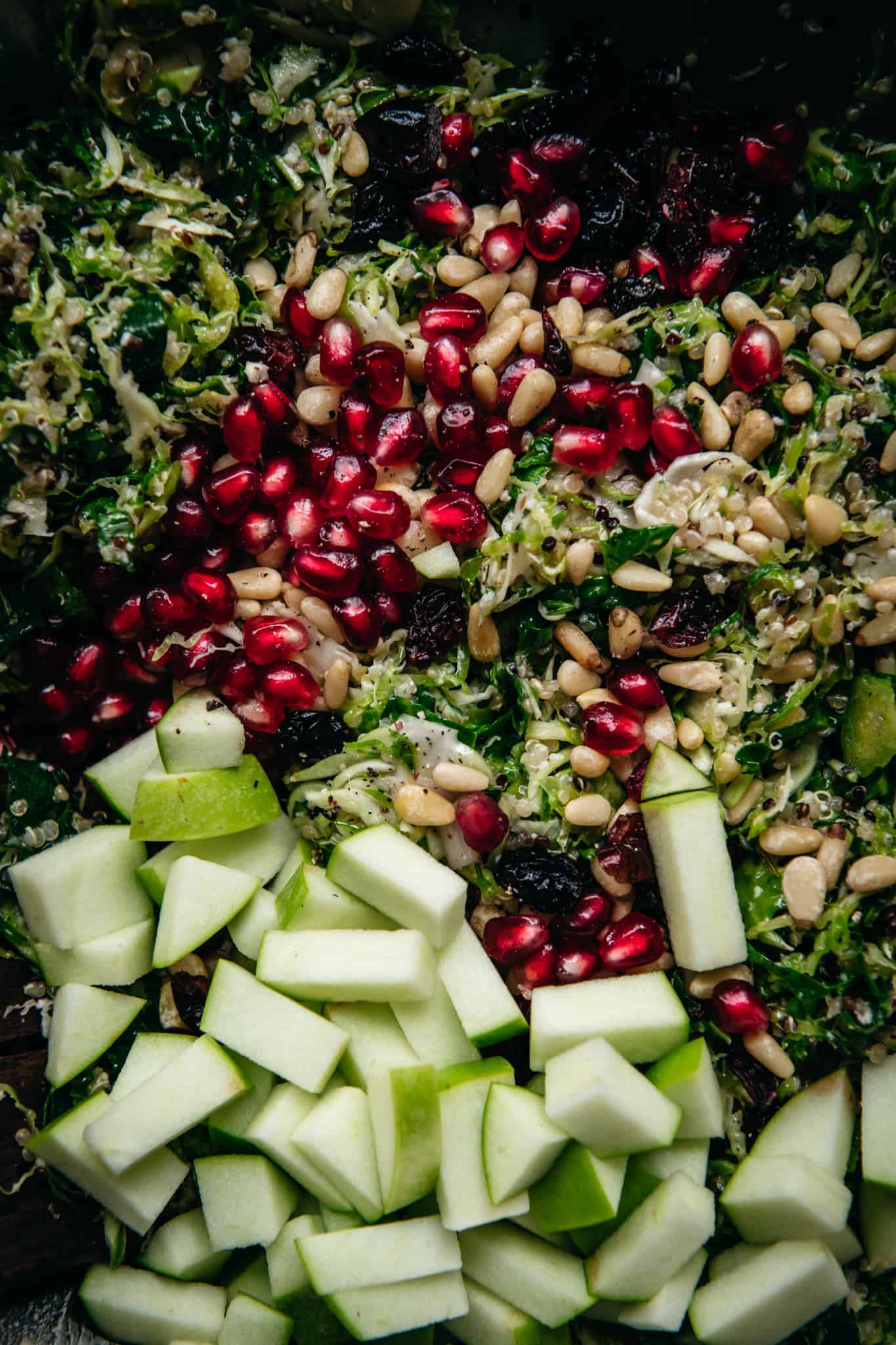 close up of shaved brussels sprouts salad before it's mixed with apples, cranberries, and pomegranate seedds