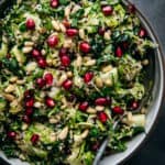 close up of shaved brussel sprout salad topped with pomegranate seeds and cranberries in a bowl