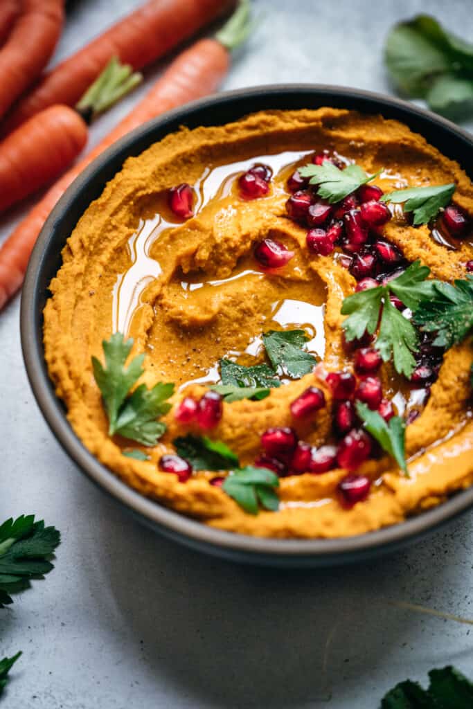 45 degree overhead of vegan smoky carrot dip in a bowl topped with pomegrate seeds