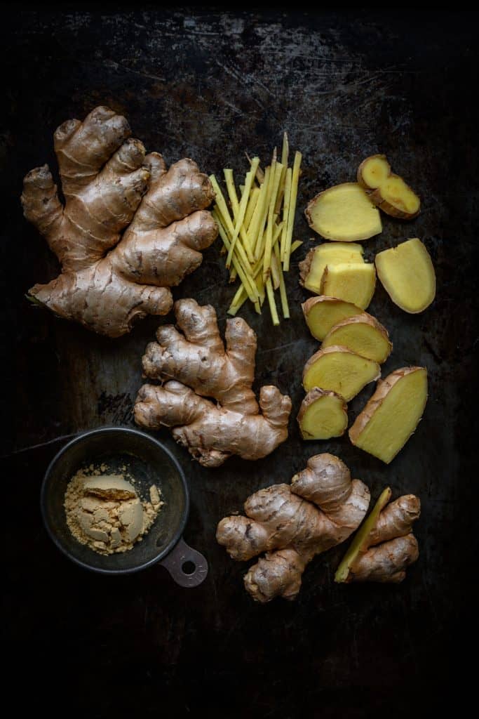 fresh and powdered ginger styled on a rustic dark background