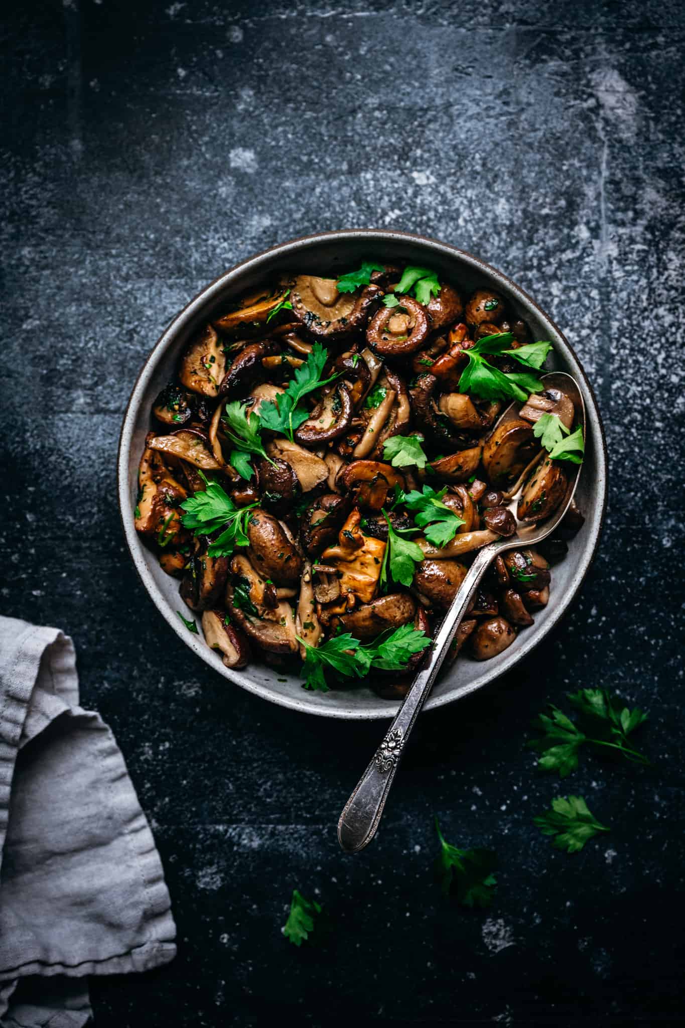overhead of pan roasted wild mushrooms in a bowl with a spoon