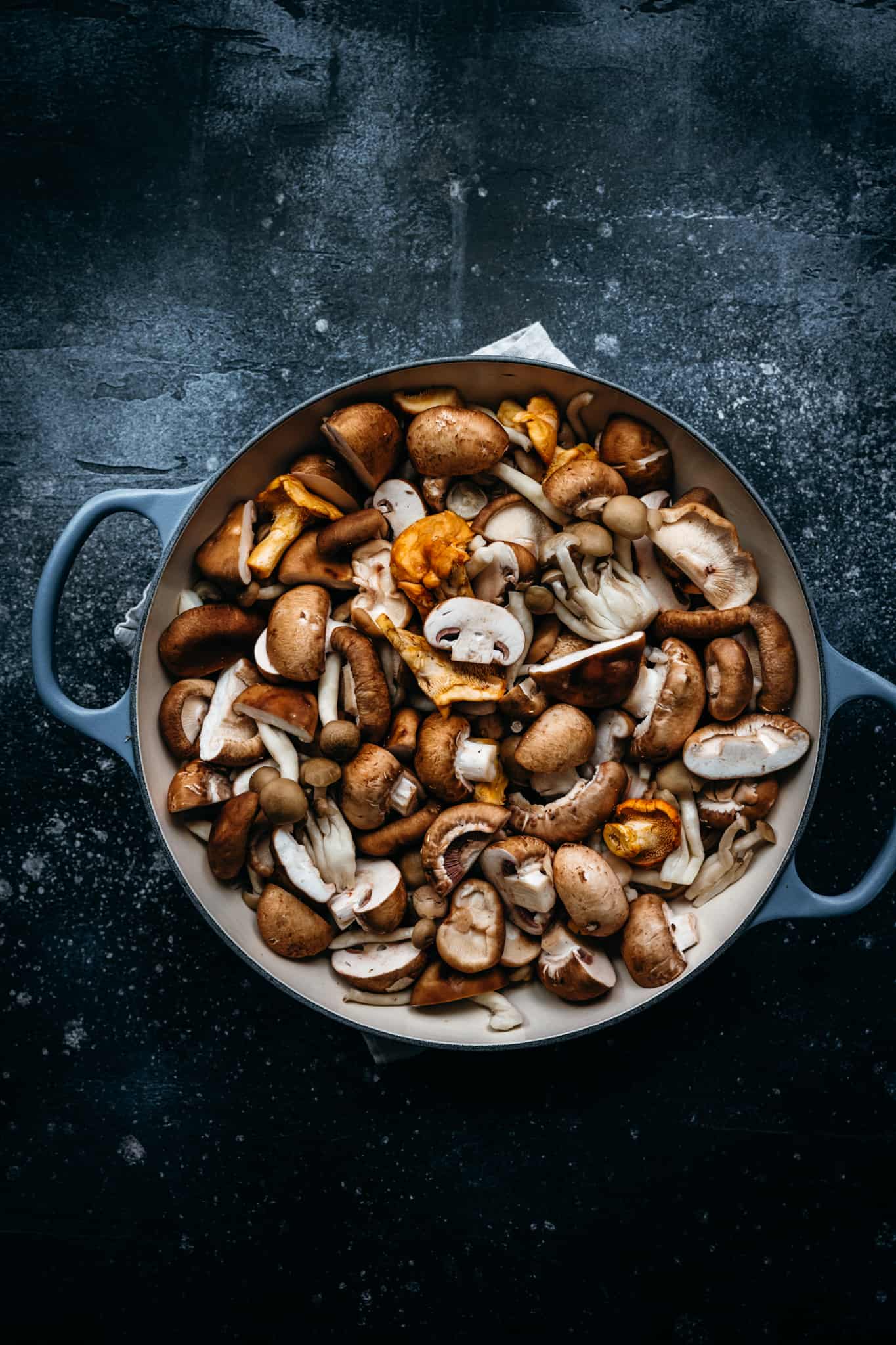 overhead of mixed wild mushrooms in a dutch oven