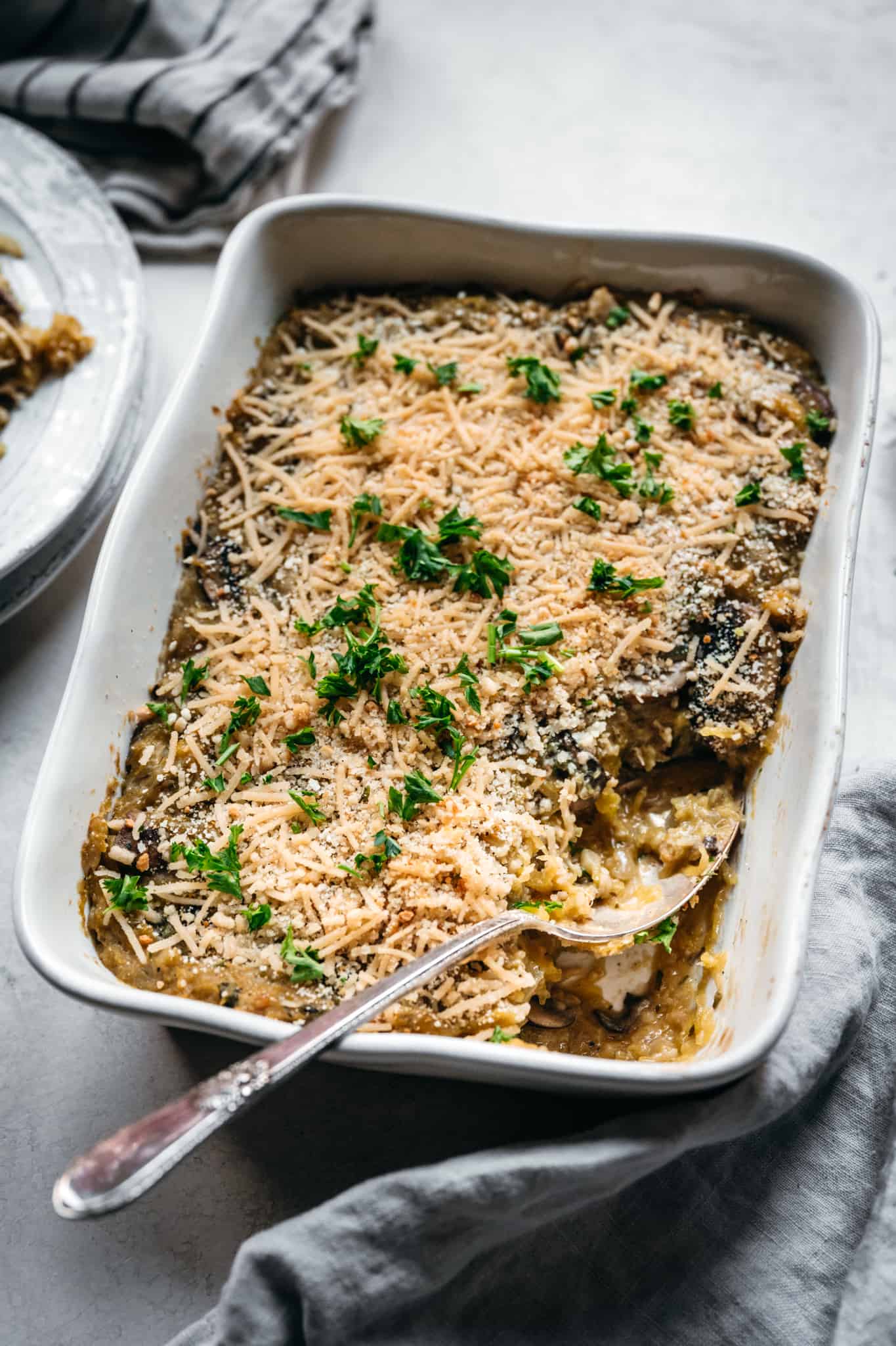 side view of vegan spaghetti squash casserole in white baking dish with spoon