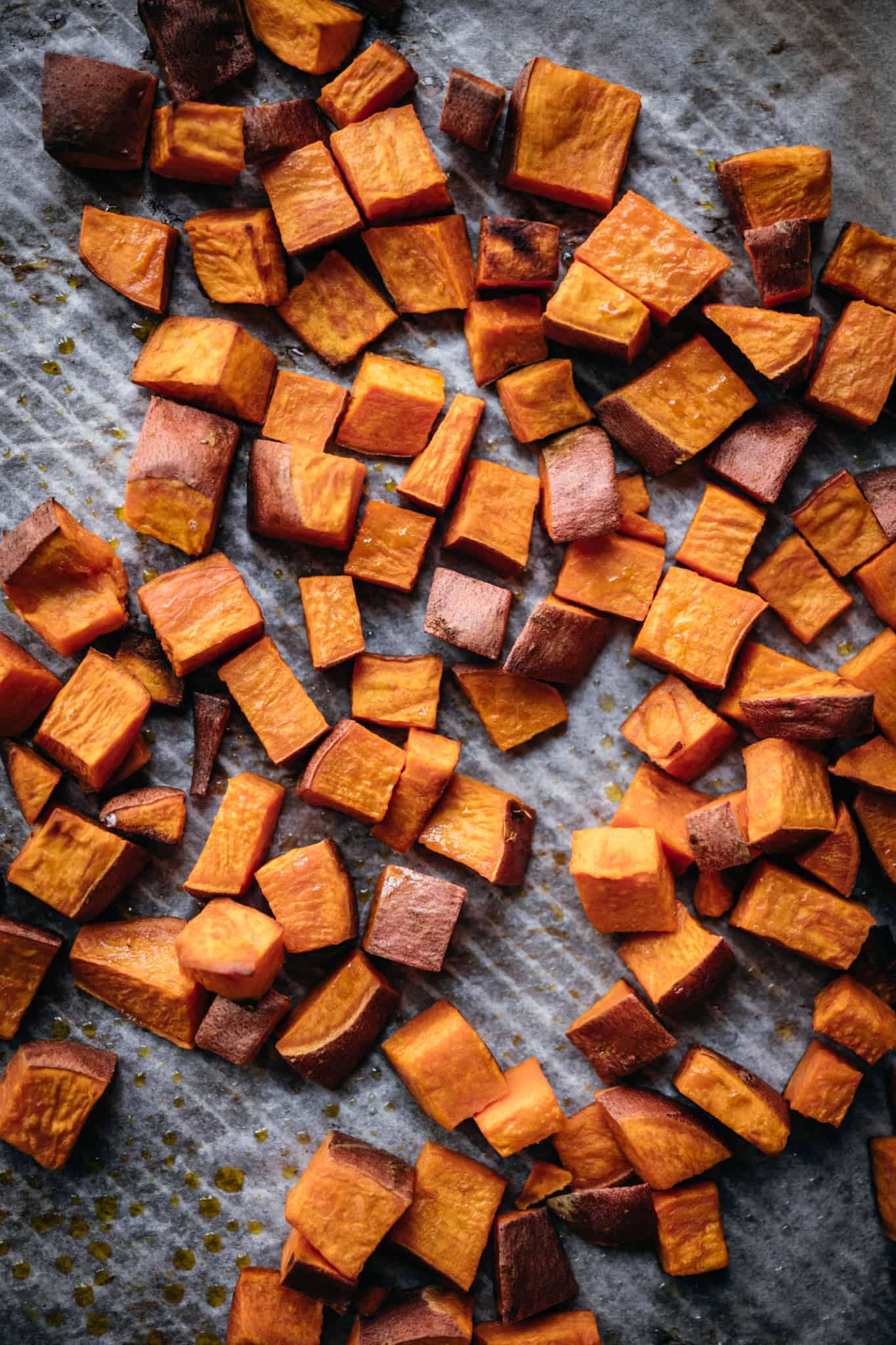 overhead view of roasted sweet potatoes on a sheet pan