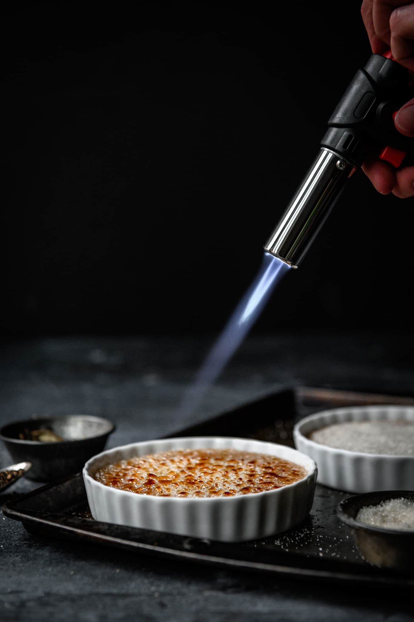 person using blowtorch to caramelize sugar for creme brulee