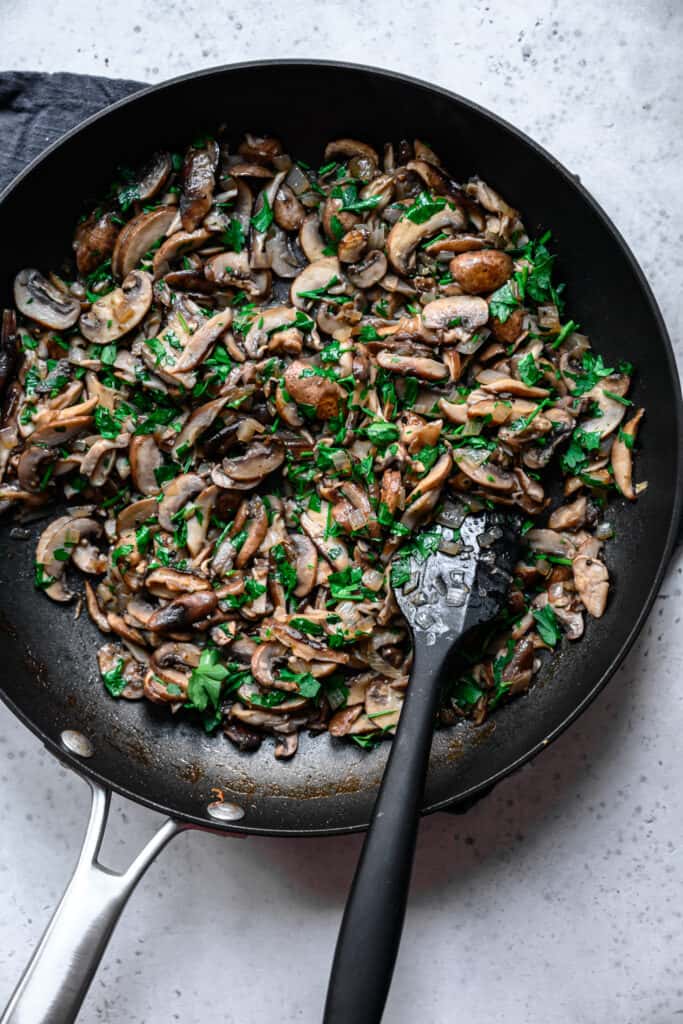 overhead view of cooked mushrooms in pan with parsley