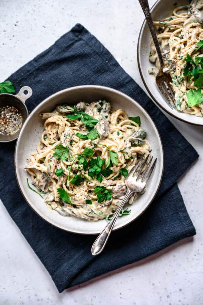 overhead view of vegan mushroom alfredo in bowl topped with parsley