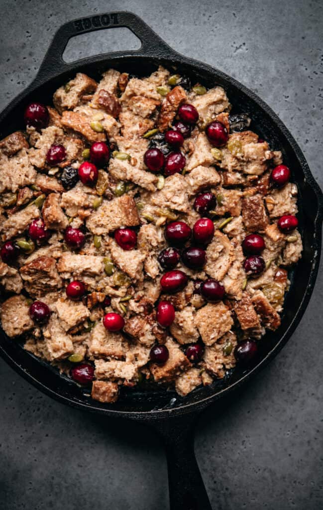overhead view of unbaked cranberry bread pudding in cast iron skillet