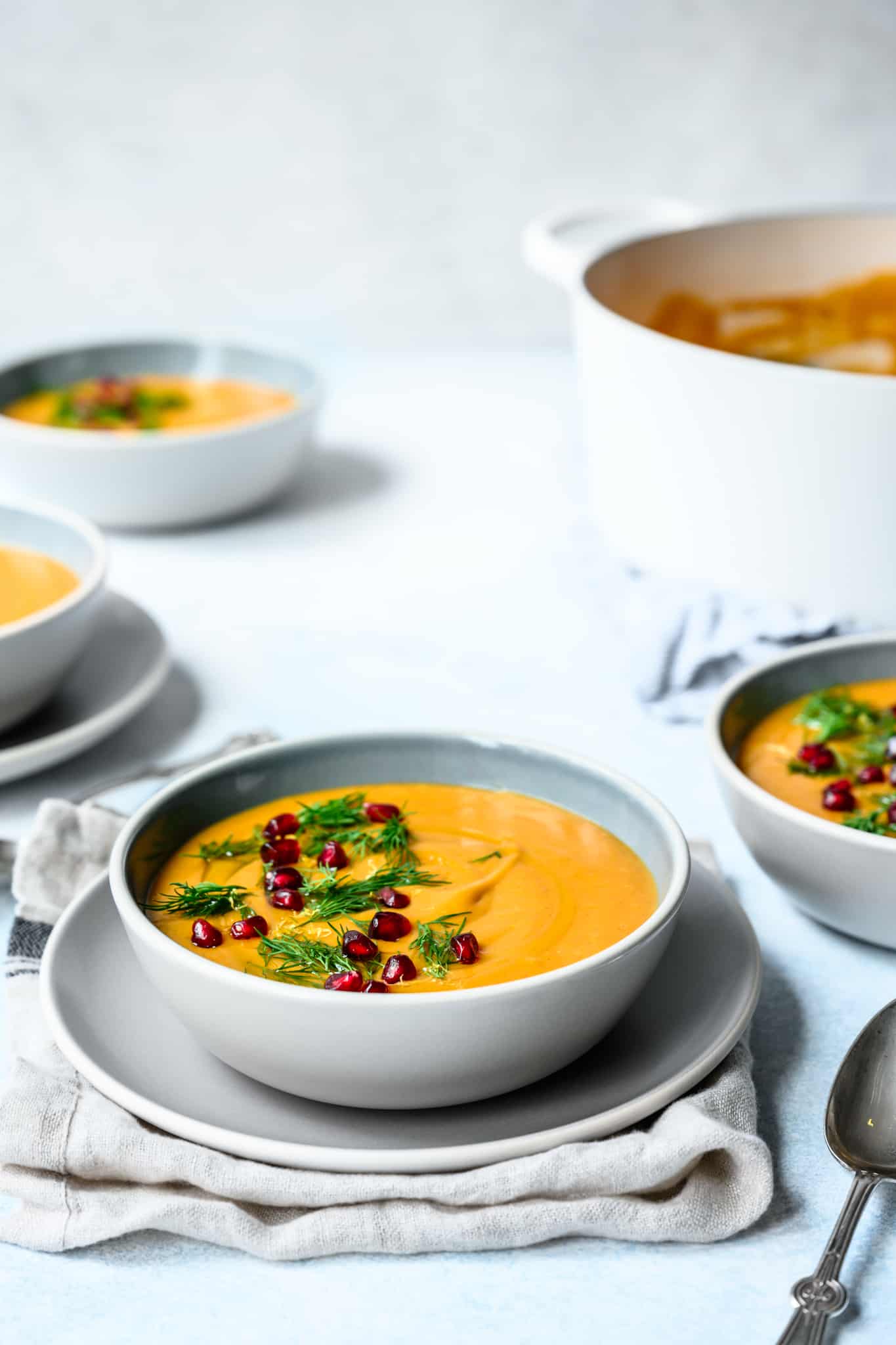 45 degree overhead of golden beet soup in a white bowl on a white plate