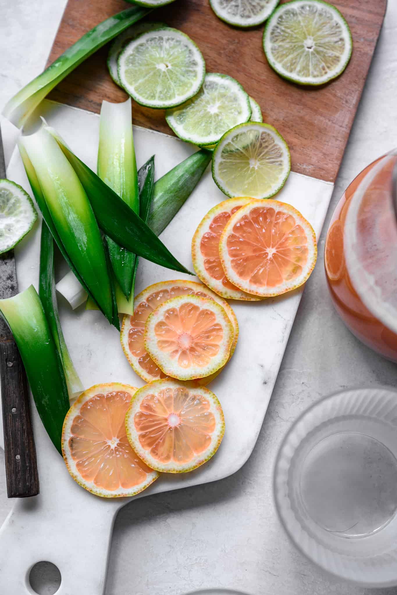 overhead view of pink lemons and limes on white marble cutting board