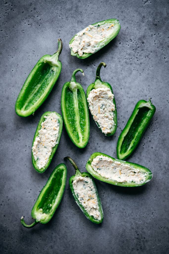 overhead of raw jalapenos, some with vegan cheese filling and some empty