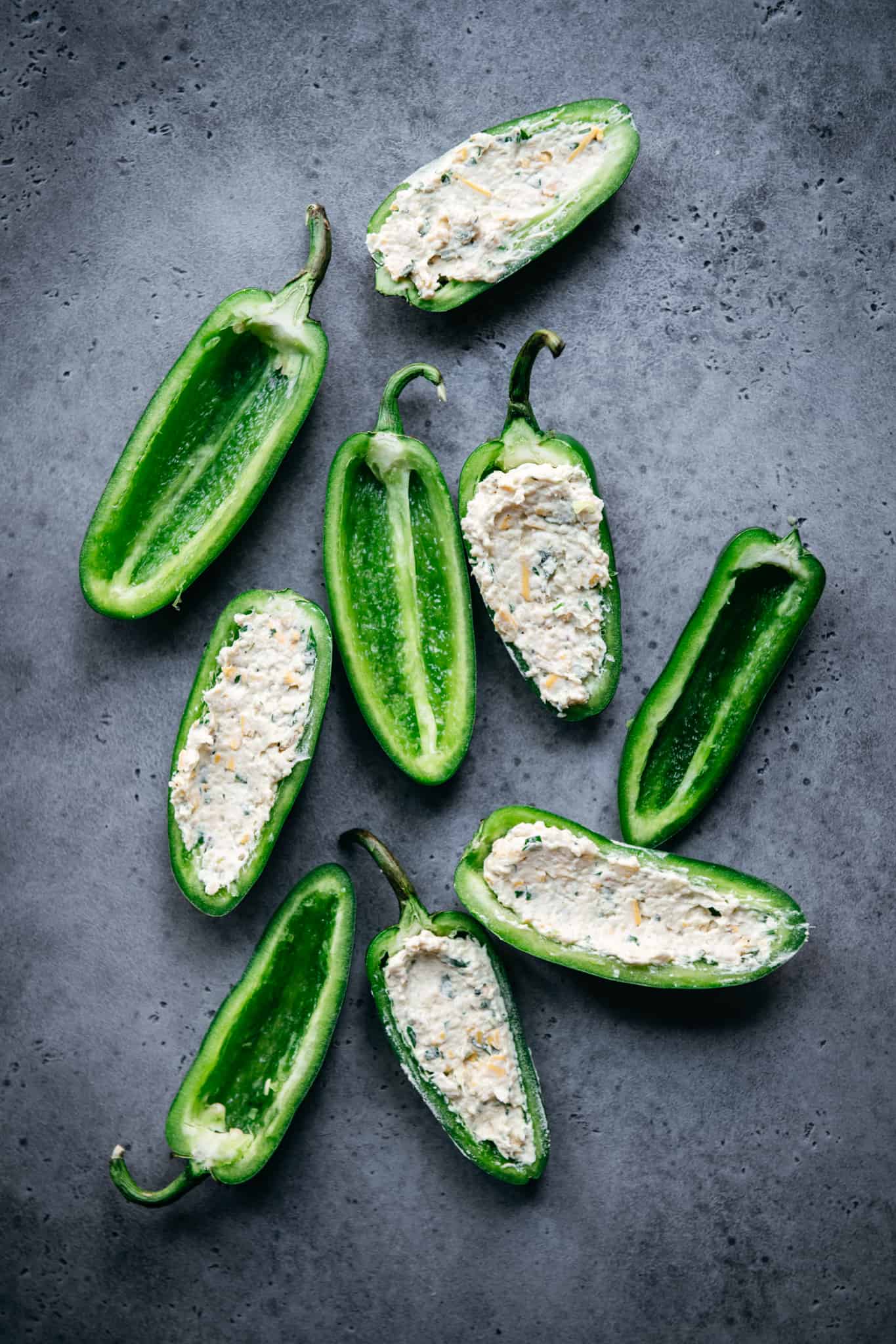 overhead of raw jalapenos, some with vegan cheese filling and some empty