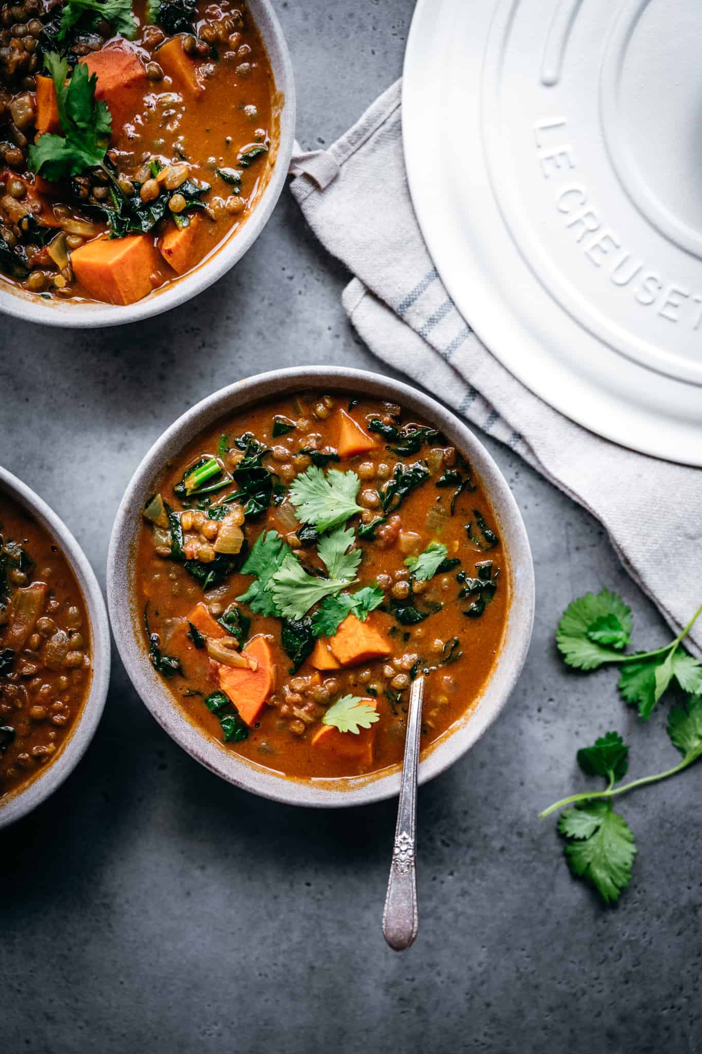 overhead view of lentil sweet potato curry soup in grey bowl with cilantro garnish