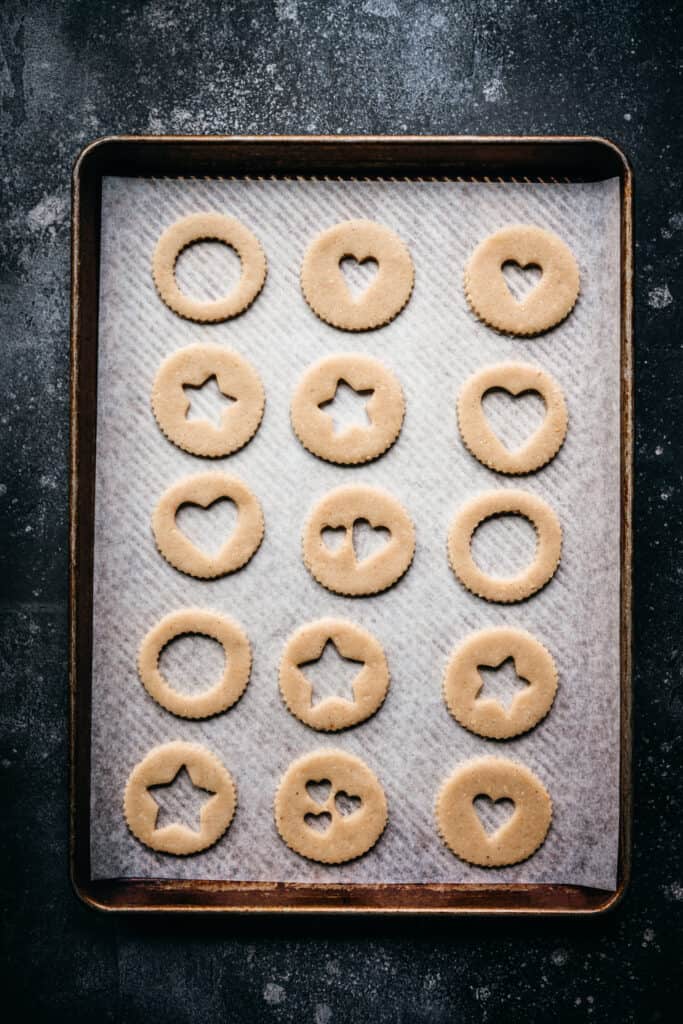 Cookie dough with heart and star-shaped cutouts on baking sheet for Valentine's Day treats.