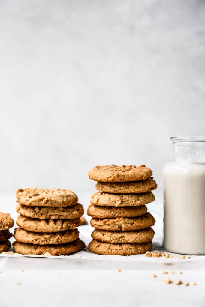 side view of two stacks of vegan gluten free peanut butter cookies next to glass of milk