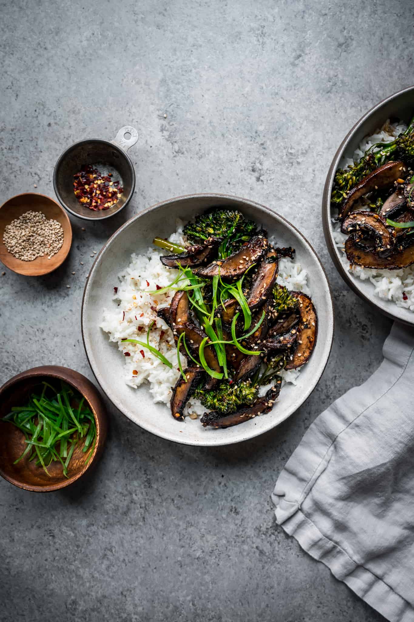 overhead of vegan teriyaki mushroom bowls on a light grey background