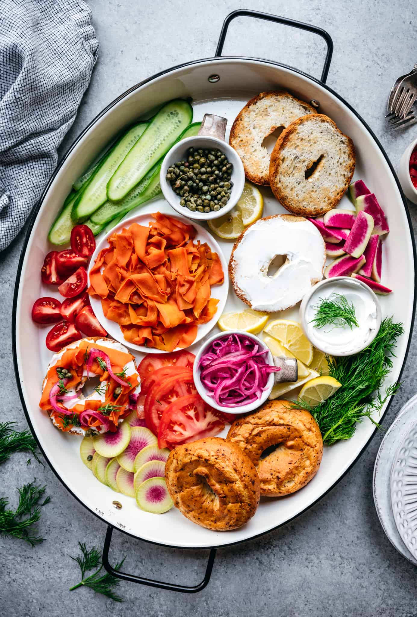 Overhead of a platter with homemade vegan carrot lox, bagels, cream cheese and other toppings for brunch