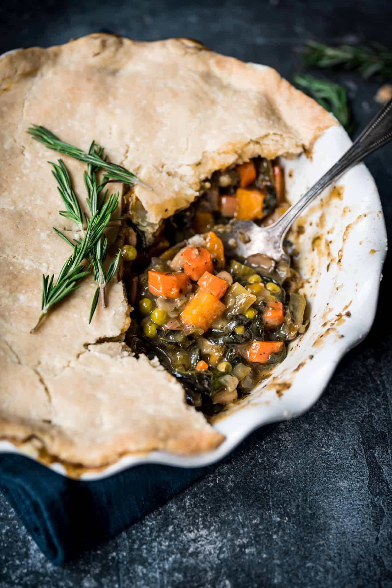 45 degree overhead of vegetarian pot pie with a piece taken out in a pie dish