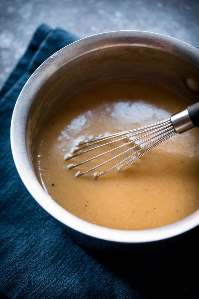45 degree overhead of vegan velute sauce in a saucepan with a whisk