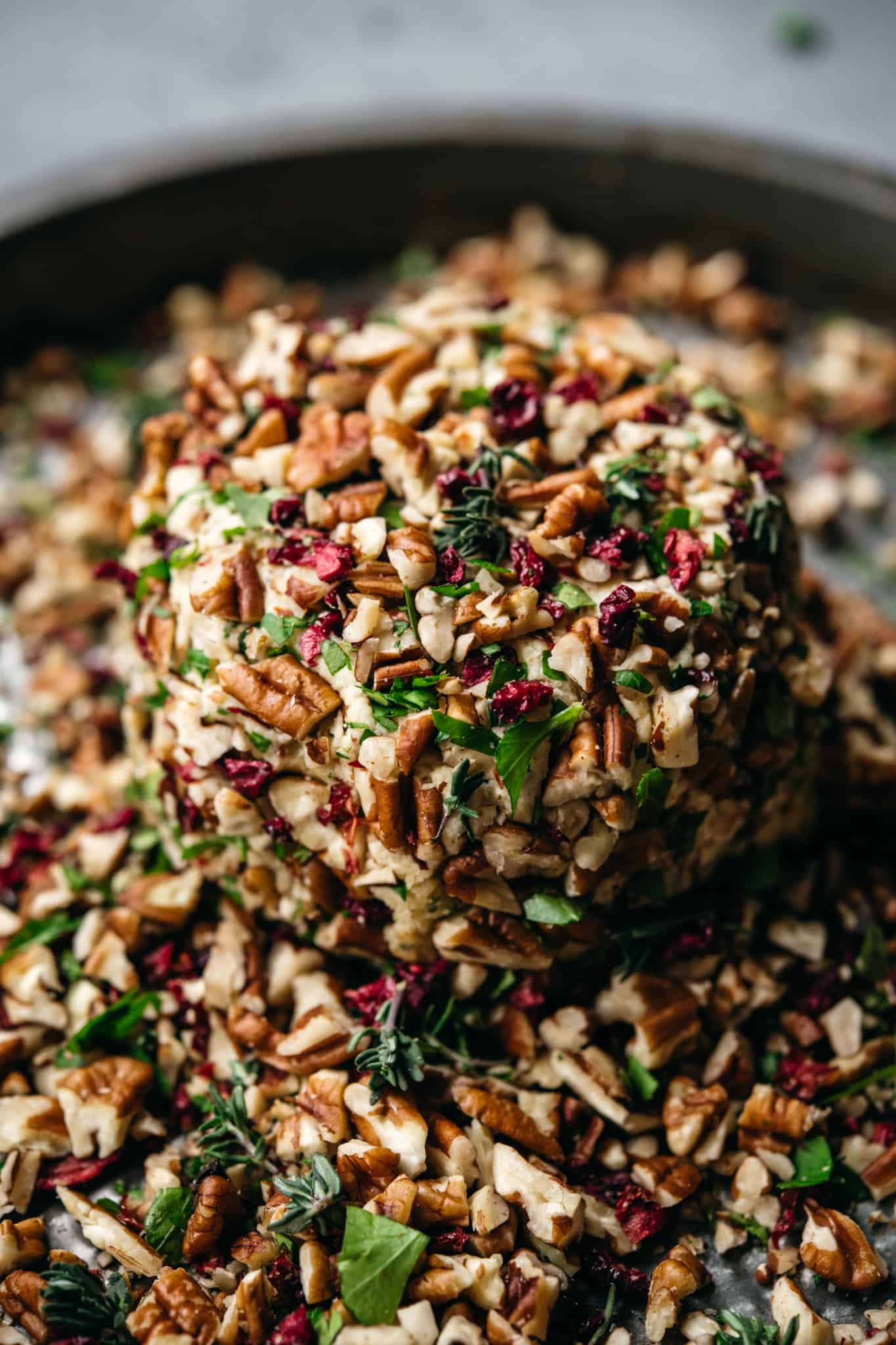 close up of vegan cheese ball sitting on the coating mixture